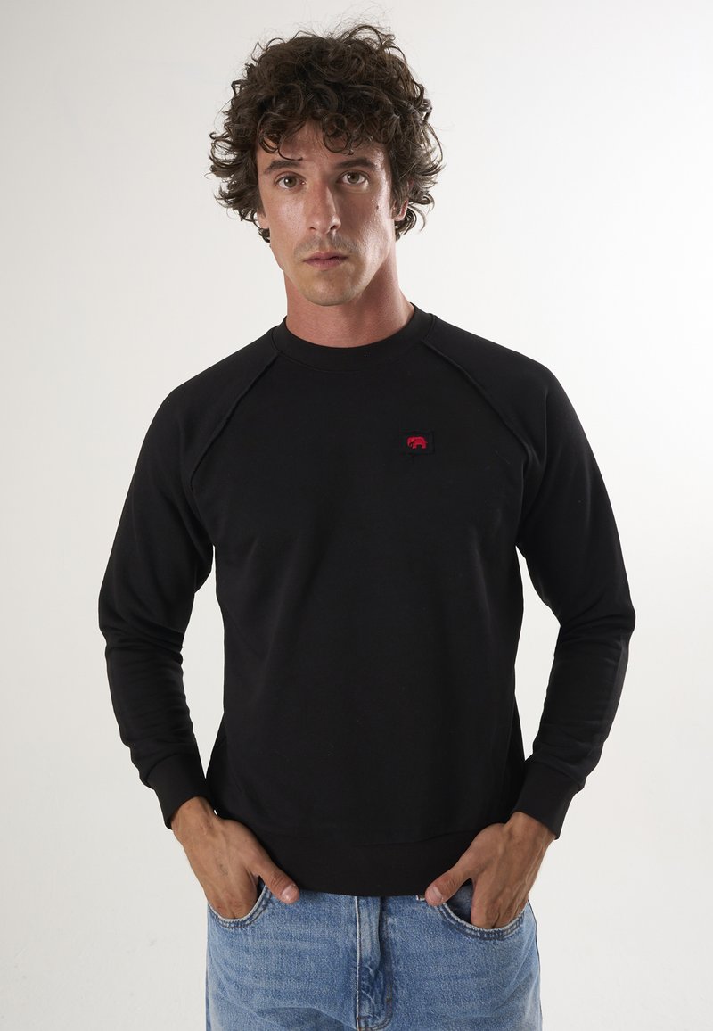 Must mustama sweatshirt, valmistatud puuvillast, ümarate väljalõigetega kaelusega, pikad raglansleeved ja väike punane logo pael rinnal.