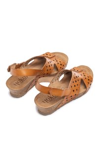 Sandalias de cuero marrón con detalles calados, correa ajustable y plantilla de corcho. Presenta una suela texturizada para mayor agarre. Diseño clásico de punta abierta.