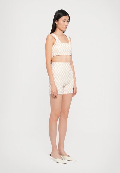 Two-piece set featuring a square-neck crop top and high-waisted shorts in a light peach color with a checkered pattern. Smooth fabric.