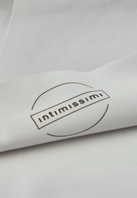 White fabric with a smooth texture featuring a circular black logo reading "intimissimi" in the center. Simple and minimalist design.