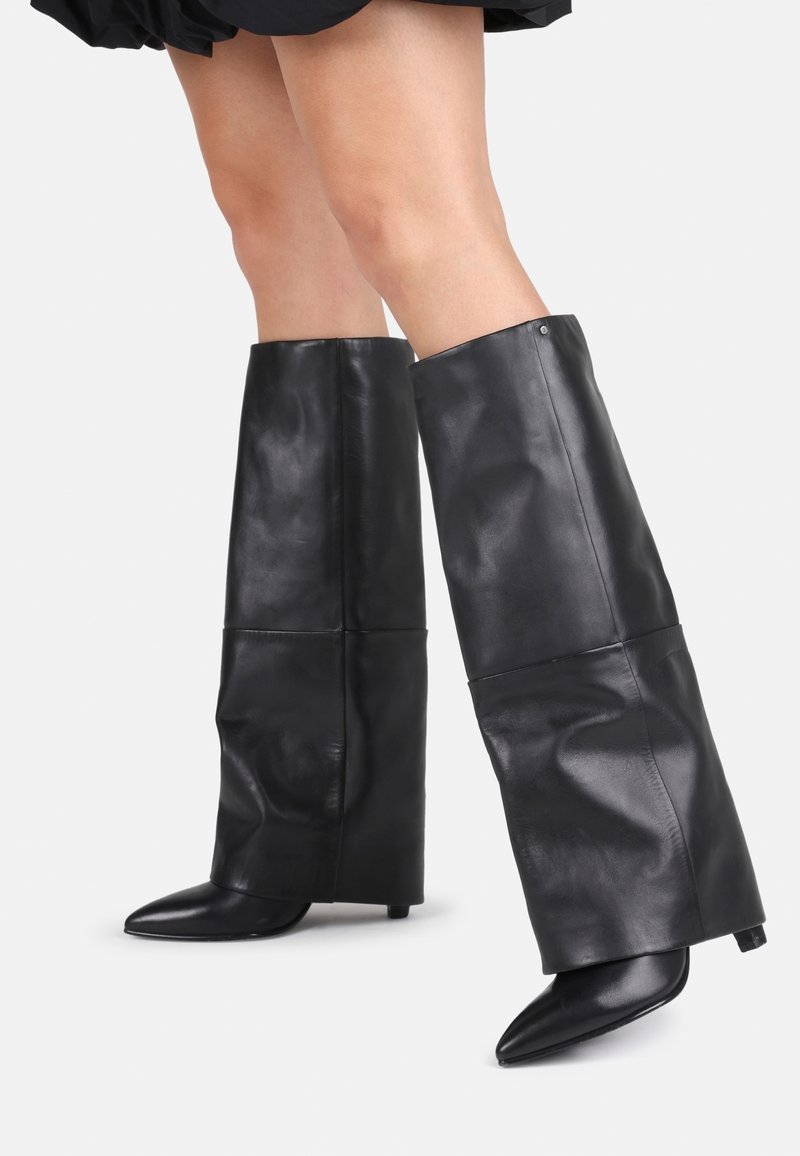 Stivali neri in pelle fino al ginocchio con design aderente, punte appuntite e tacco spesso e strutturato. Presentano una texture liscia e dettagli cuciti.