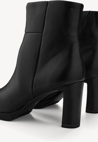 Bottes courtes en cuir noir à texture lisse, design droit et talon bloc haut. Présentent des coutures minimalistes et aucun accent visible.