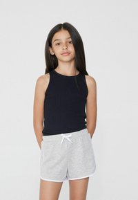 Zwarte mouwloze top gecombineerd met grijze shorts met witte accenten en een trekkoord aan de voorkant. Eenvoudig, casual ontwerp met minimale details.