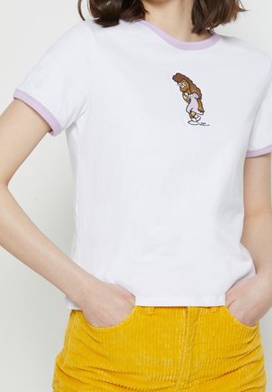 Biały t-shirt z lawendowym wykończeniem, noszony przez osobę, z małą kreskówką przedstawiającą kobietę z kręconymi włosami w lawendowej sukience na środku klatki piersiowej.