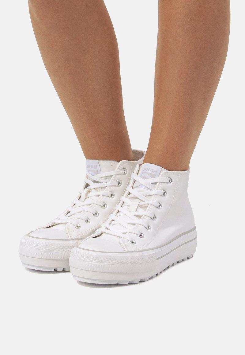 Baskets montantes blanches en toile avec une semelle en caoutchouc, dotées d'un laçage, d'un bout rond et d'une marque discrète sur la languette.