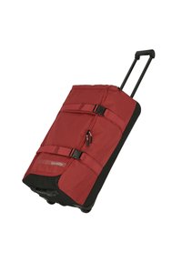 Bolsa de viaje de ruedas rojas, hecha de un tejido con superficie texturada, con acentos negros, dos correas de compresión y un mango telescópico.