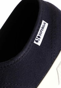 Sneaker in tela navy con suola in gomma bianca, punta rotonda e dettagli cuciti. Presenta una piccola etichetta logo "Superga" bianca sul lato.