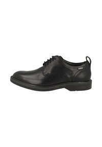 Zwarte leren dresschoenen met een ronde neus, gestructureerd oppervlak, vetersluiting, lage hak en een klein treklipje aan de achterkant.