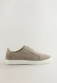 Baskets slip-on en daim taupe avec semelle en caoutchouc blanche, design minimaliste et détails de couture subtils sur fond neutre.