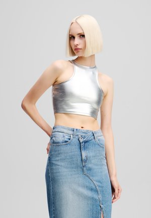 Ezüst fényes, rövidített tank top magas nyakkal, világoskék farmer midi szoknyával párosítva, amely oldalhasítással és klasszikus öt zsebes kialakítással rendelkezik.