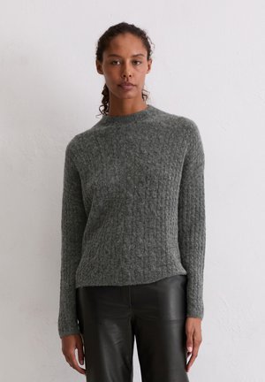 Pull en maille côtelée gris avec des manches longues et un col rond, associé à un pantalon en cuir noir. Texture douce avec une silhouette ajustée.