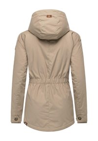 Beige hættejakke med indsnævret talje, lange ærmer og knaplukninger ved håndleddene. Har et mærke på ryggen og en glat stofstruktur.