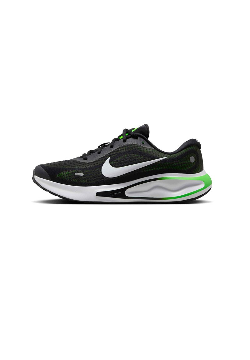 Sort sportssko med mesh-overdel, grønne detaljer og en hvid swoosh-logo. Har en slidstærk ydersål og polstret sål for støtte.