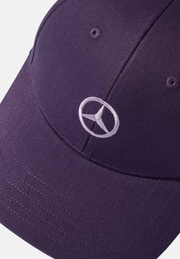 Gorra morada hecha de tela, con un patrón texturizado. En la parte frontal presenta un logo de Mercedes-Benz bordado en blanco.