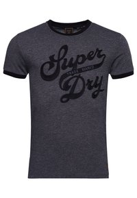 Camiseta de manga corta gris oscuro con cuello y bordes de las mangas negros, que presenta el texto "Super Dry" y "Trade Mark'd" en una gran fuente cursiva en el frente.