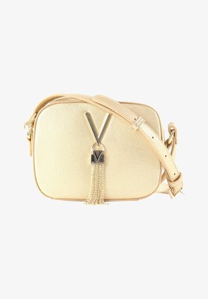 Sac bandoulière beige texturé avec sangle ajustable, emblème métallique "V" et détail pompon en chaîne dorée à l'avant.