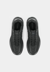 Sapatos atleticos pretos com material sintético texturizado, design curvado e solas de borracha. Apresentam atacadores pretos e detalhes em cinza no logótipo.