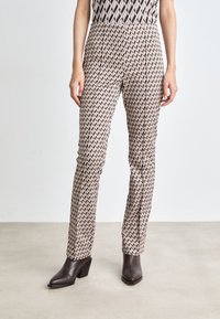 Bedruckte Hosen aus weich material, mit einem geometrischen Muster in Creme, Braun und Schwarz. Schmal geschnitten mit einer mittelhohen Taille und nahtlosem Design.