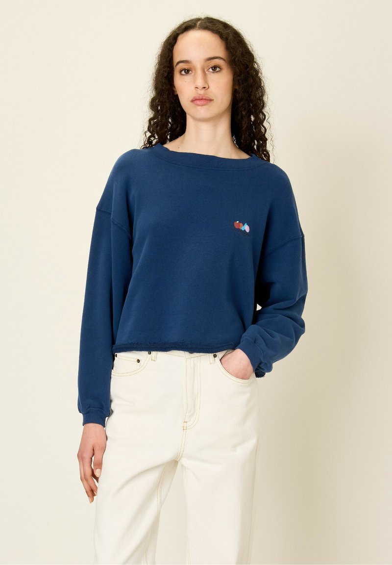 Felpa blu corta con maniche lunghe, caratterizzata da un piccolo design multicolore ricamato sul petto e un dettaglio di orlo grezzo.