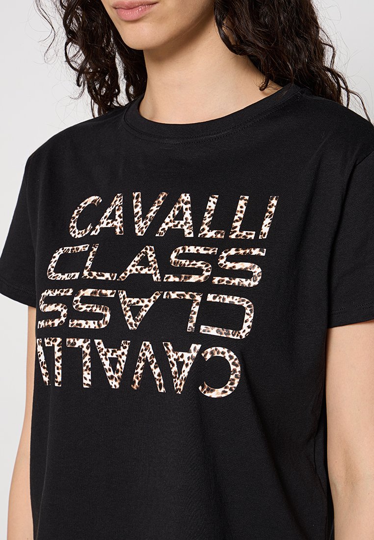 Donna che indossa una maglietta nera con testo in stampa leopardata "CAVALLI CLASS" specchiato e ripetuto due volte sul davanti.