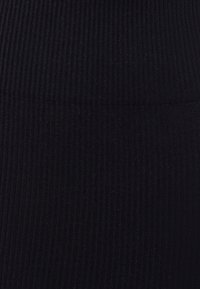 Svart ribbad tyg med en texturerad yta, som visar ett enhetligt mönster av vertikala ränder och en slät finish.