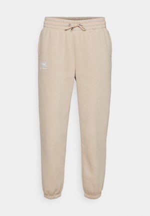 Šviesiai rudos spalvos sportinės kelnės, pagamintos iš minkštos medžiagos, su elastinga juosta ir raišteliu, su raukšlėtomis rankovėmis ir mažu logotipu kairėje šlaunyje.