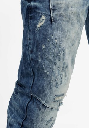 Verbleekte blauwe jeans van denim met een verweerd uiterlijk, voorzien van rafelige stukken en een versleten effect op het kniegebeid.