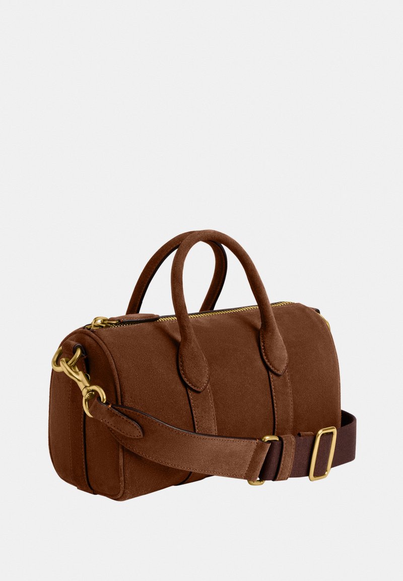 Sac à main cylindrique en daim marron avec deux poignées, anse d'épaule ajustable et détails en métal doré sur la fermeture éclair et la quincaillerie.