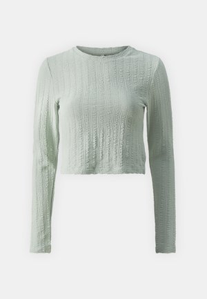 Light green cropped long-sleeve top made of textured fabric with a ribbed pattern and round neckline. Soft finish, lightweight design.