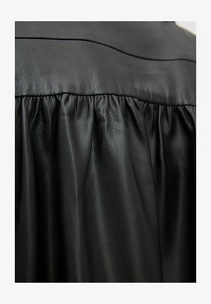 Robe en cuir noir avec une taille froncée, texture lisse et éclat subtil, présentant des détails de corsage structuré.