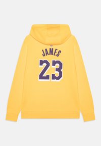 Felpa gialla con il testo "JAMES" in viola e il numero "23" sul retro. Materiale misto cotone, vestibilità standard e tasca a marsupio.