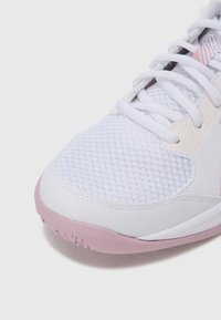 Λευκό αθλητικό παπούτσι με πλέγμα στο πάνω μέρος και ροζ λαστιχένια σόλα. Δι αθέτει σύστημα δέσης με κορδόνια, διακριτικές ραβδώσεις και επενδεδυμένο γιακά για υποστήριξη.