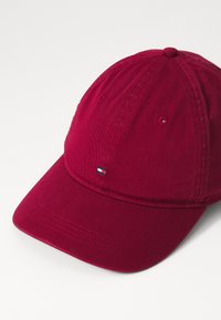 Cappellino da baseball in cotone rosso con visiera curva e piccolo logo ricamato sul davanti. Presenta fori di ventilazione e tessuto testurizzato.