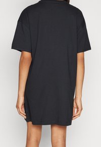 Czarny oversize t-shirt, krótki rękaw, luźny krój, materiał bawełniany, okrągły dekolt, sięgająca do połowy uda, minimalistyczny design bez zdobień.