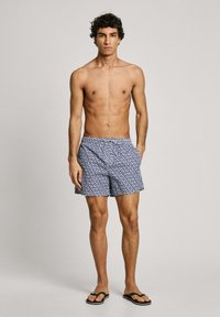 Costumi da bagno blu navy con un motivo floreale bianco. Realizzati in materiale leggero, con vita elastica e tasche laterali.