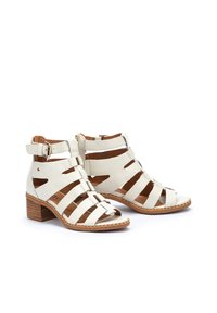 Sandalias de cuero blancas con diseño de tiras abiertas, que cuentan con una plantilla acolchada y un tacón cuadrado, acentuadas con una suela marrón.