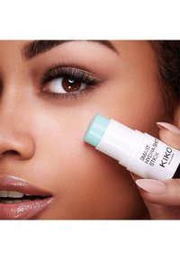 Smart Hydra Shot Stick di KIKO, forma cilindrica, base bianca, parte superiore azzurro chiaro. Applicato sulla pelle, ha una texture liscia e un aspetto leggero.