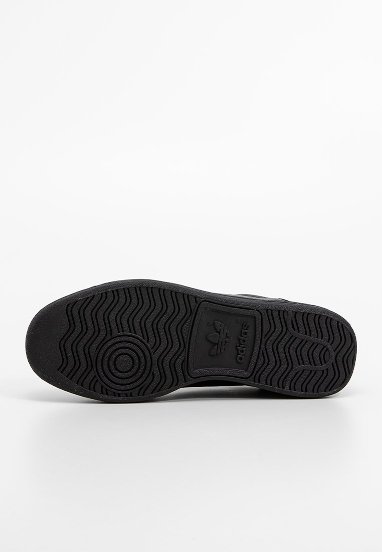 Czarna podeszwa buta Adidas z okrągłymi i falistymi wzorami bieżnika, logo Adidas wytłoczone w środkowej części stopy.
