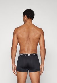 Sorte Nike boxer shorts med en mærkevare-elastik i taljen, med et tætsiddende design og glat tekstur, vist fra bagsiden.