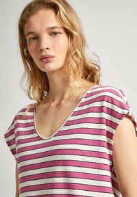 Dryžuota palaidinė šviesiai rožinės, baltos ir juodos spalvos. Turi gilų V formos iškirpimą, trumpas rankoves ir minkštą, lengvą medžiagą.