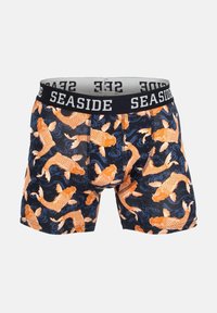 Un caleçon avec un fond bleu marine orné d'un motif de carpes koï orange et de vagues bleues. Ceinture élastique marquée "SEASIDE".