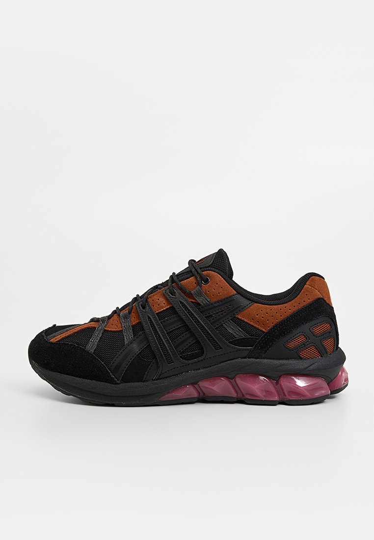 Scarpa sportiva nera e arancione con tomaia in mesh, dettagli in suede e suola di colore viola con elementi di ammortizzazione segmentati.