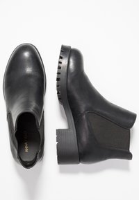 Musta nilkkurit, joissa on sileä nahkapäällinen, joustavat sivupaneelit ja paksu, uritettu kumipohja pitoon.