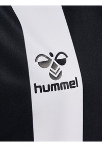 Svart och vit sporttröje tyg med ett vertikalt randigt mönster och en framträdande Hummel-logotyp i svart. Slät textur.