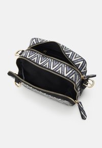 Small rectangular bag with a geometric black, white, and gray pattern. Gold zipper and hardware; interior is black fabric with a pocket.