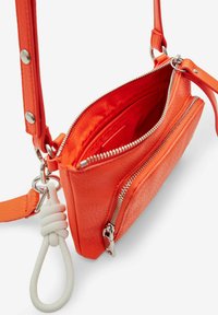 Borsa a tracolla arancione in pelle con finitura texturizzata, scomparti con zip, dettaglio della tracolla a loop bianco e hardware in tonalità argento.