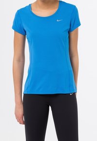 Modré sportovní tričko z prodyšné síťoviny s krátkými rukávy a kulatým výstřihem. Na prsou malé stříbrné logo Nike. Kombinováno s černými legínami.