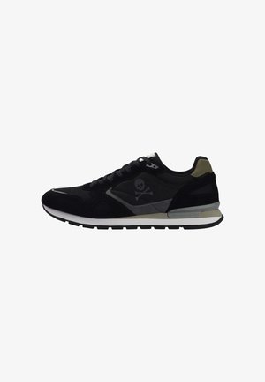 Zapatilla deportiva negra con parte superior de ante y malla, acentos en gris contrastante, logo de calavera y huesos cruzados, y suela blanca.