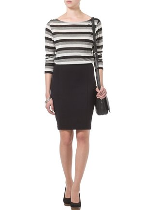 Gestreiftes schwarz-weißes Langarmoberteil, kombiniert mit einem schwarzen Bleistiftrock. Das Outfit wird mit schwarzen High-Heels und einer Schultertasche abgerundet.