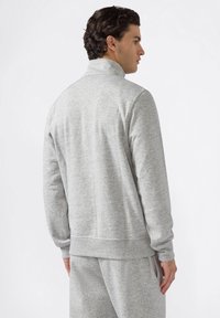 Pullover grigio con colletto alto, maniche lunghe e polsini a coste. Realizzato in un tessuto morbido con una texture liscia e cuciture minime.